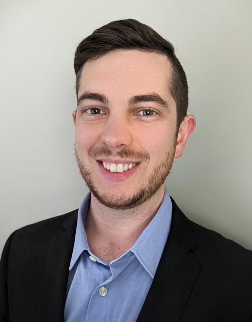 picture of Dan Sabelli smiling in a black suit and blue shirt
